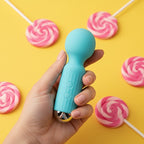 Get Closa blue silicone mini wand vibrator held in hand against a yellow background with pink swirl lollipops.